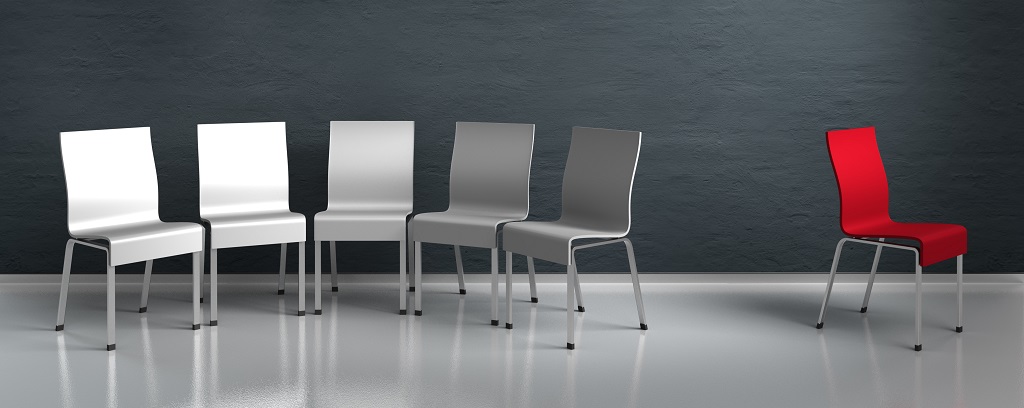 Photo of five silver chairs in a group and one red chair left all alone.