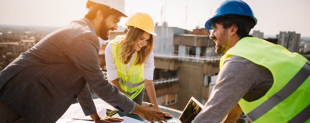 Photo of three workers on a job site. One wears a business suit and appears to be a supervisor.