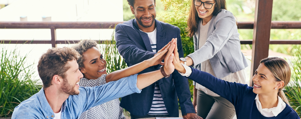 Photo of multiple employees touching hands and smiling.