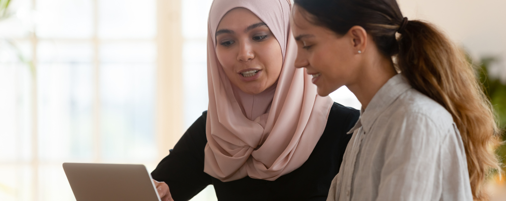 Photo of two people at work, one mentoring the other.