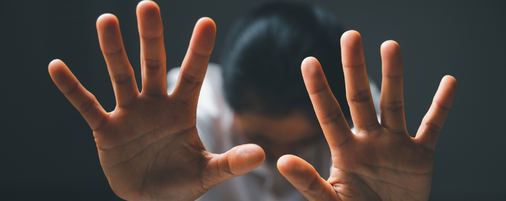Photo of person communicating a direction to stop: arms extended, hands up, fingers spread.