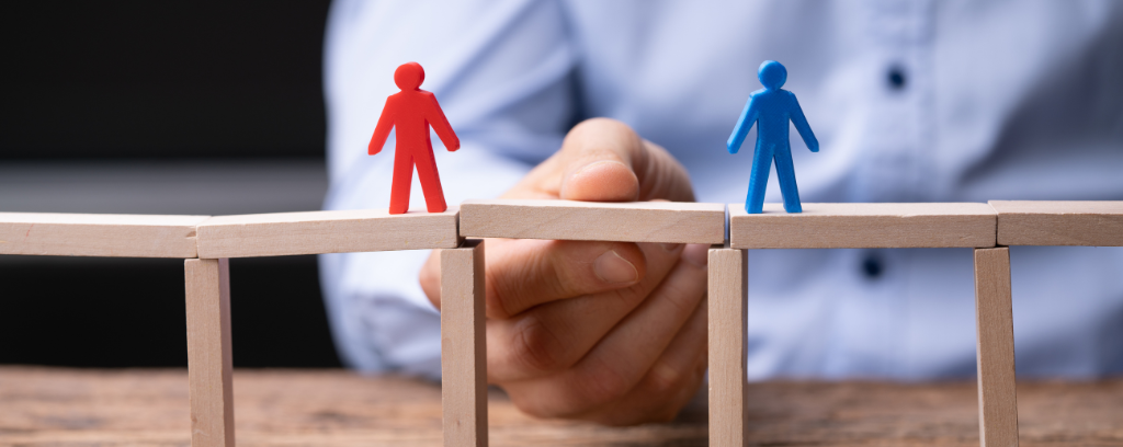 Photo of two people figures on platforms while a hand places a bridge between them