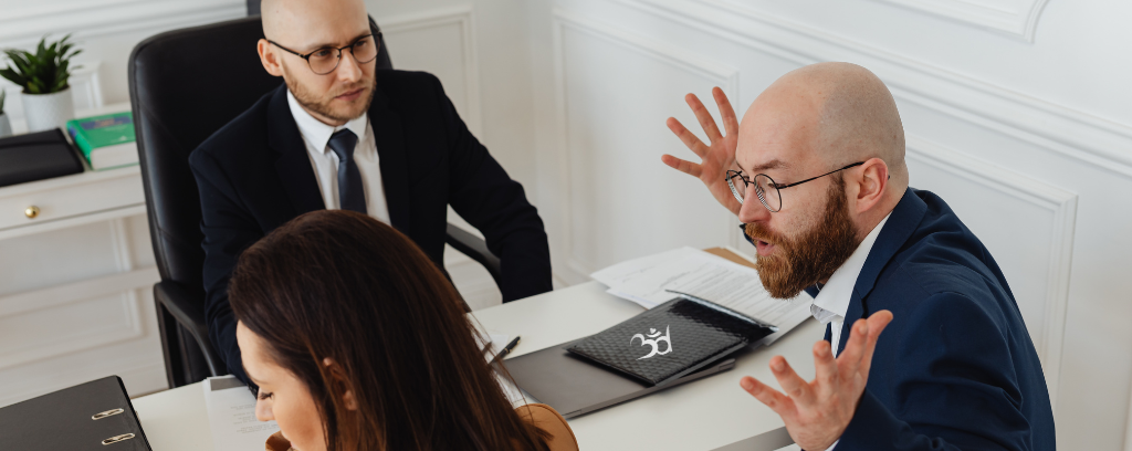 Photo of co-worker throwing hands in air and verbally attacking another while a third looks confused