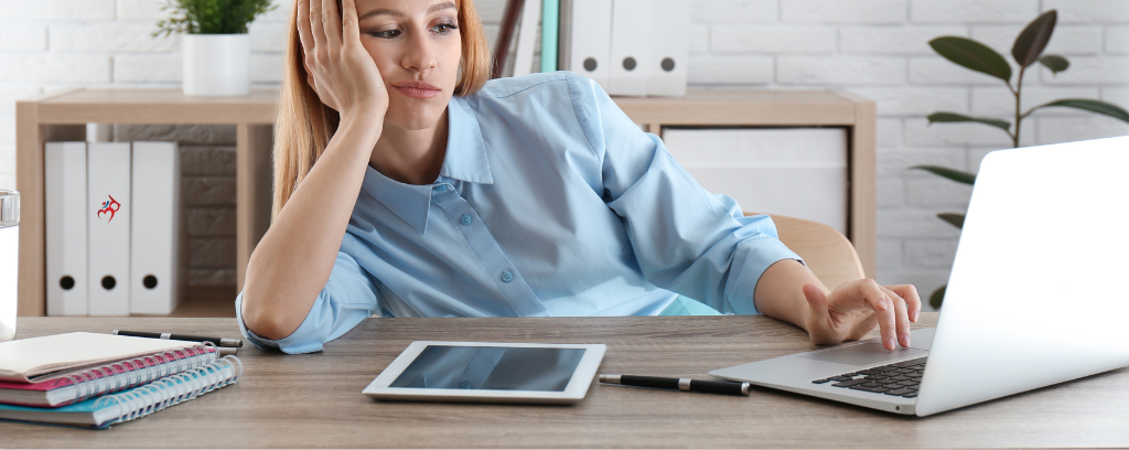 Photo of worker with head propped up on desk with one hand and boredom expression