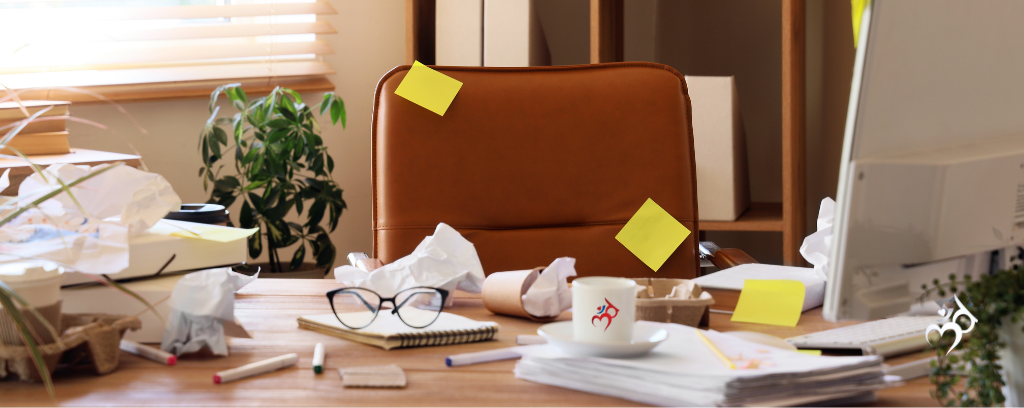 Photo of messy office desk with papers, sticky notes, coffee cup, eyeglasses, etc.