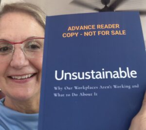 Photo of Nance L. Schick holding an Advance Reader Copy of UNSUSTAINABLE