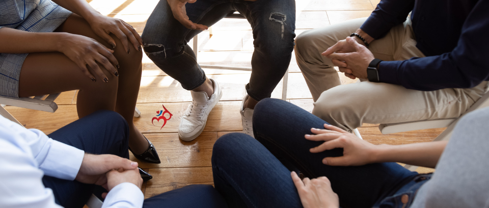 Photo of employees seated in a circle and sharing safely