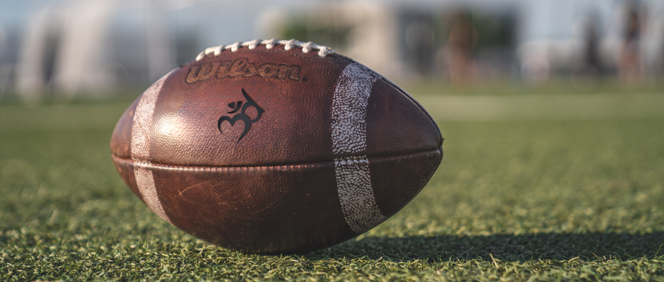 Photo of football on field with Third Ear CR logo